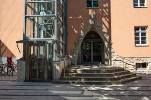 Eingang eines orangefarbenen Gebäudes mit Treppe und Fahrstuhl