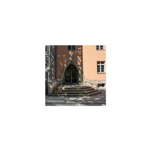 Eingang eines orangefarbenen Gebäudes mit Treppe und Fahrstuhl